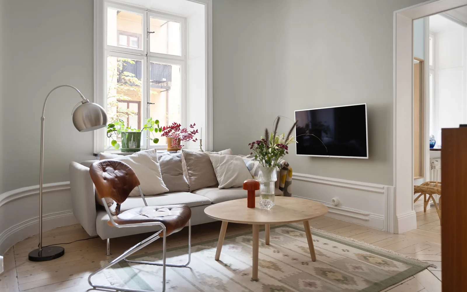 Lys stue med sofa, tregulv og store vinduer